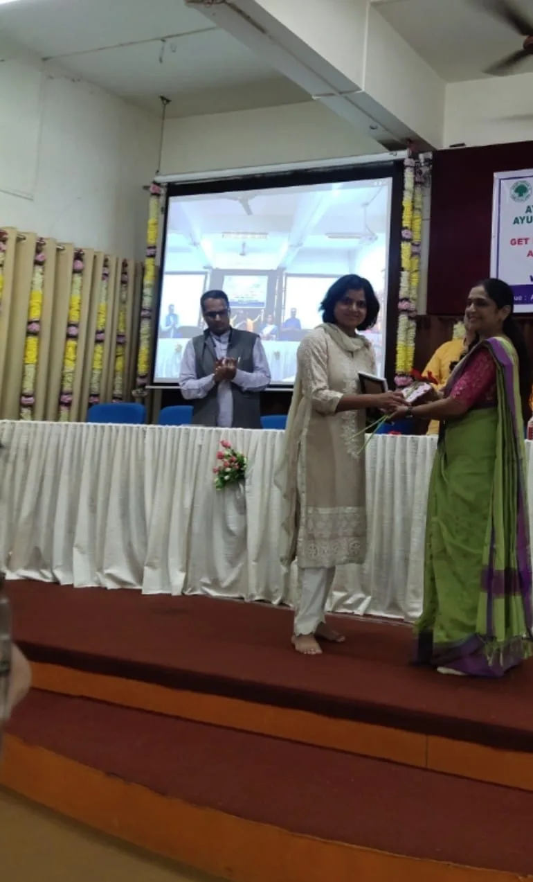 Dr. Adv. Mohini Suryawanshi receiving flowers and a commemorative presentation at an academic programme.
